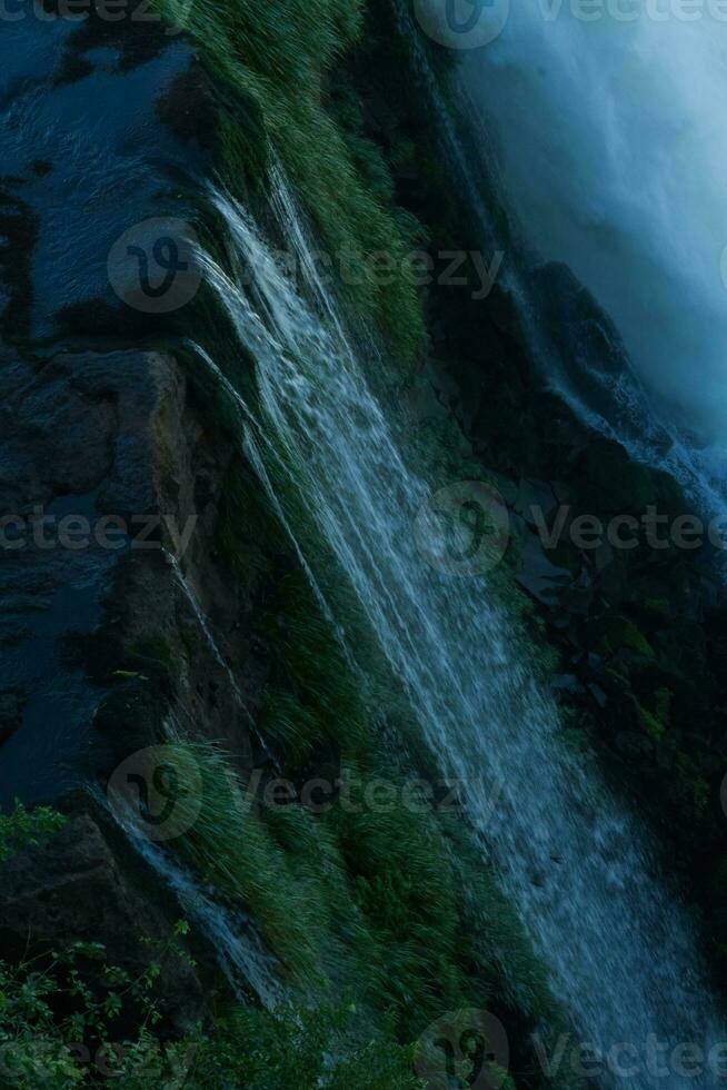 Iguazu Falls on the border between Argentina and Brazil with beautiful rainbows and lots of vegetation and lots of water falling down them photo