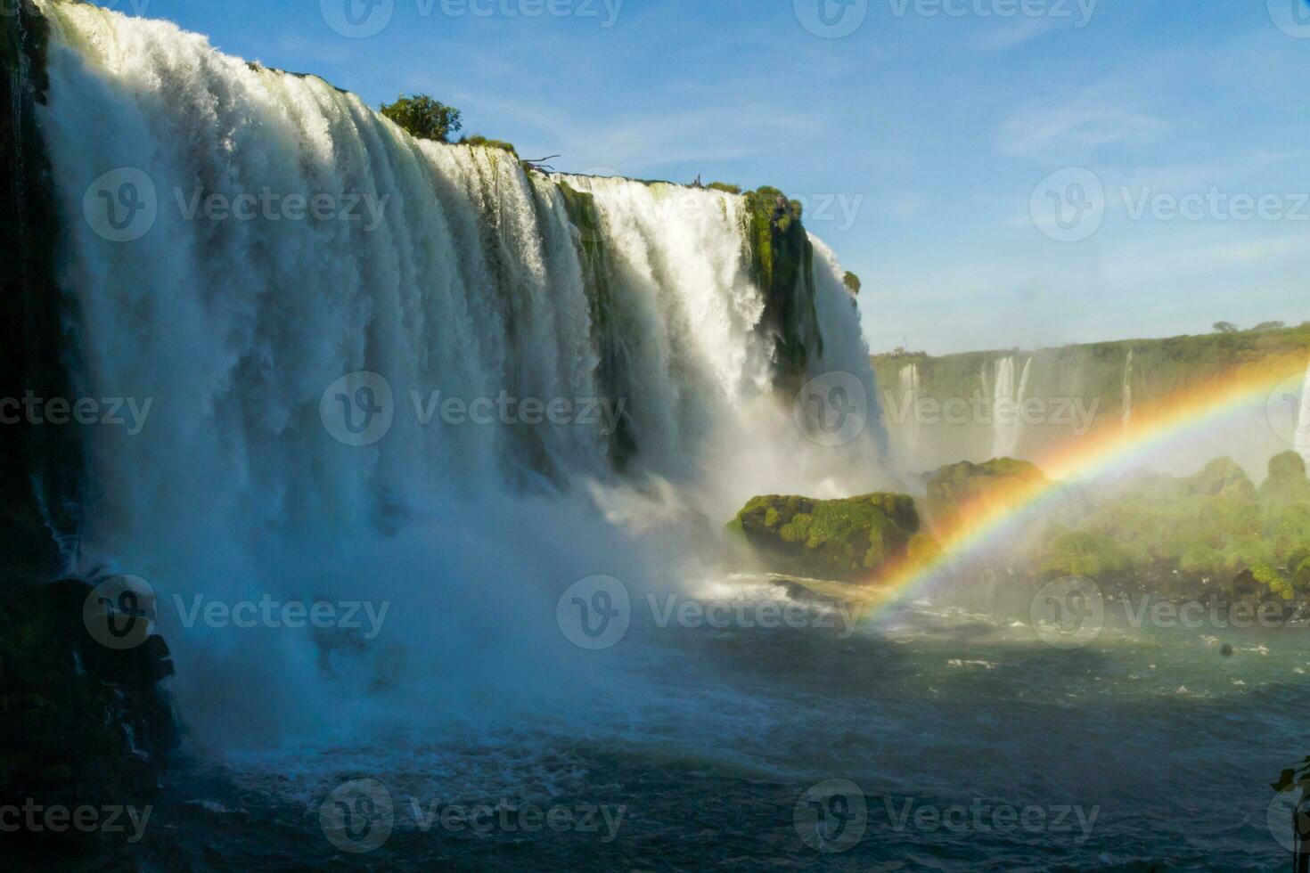 Iguazu Falls on the border between Argentina and Brazil with beautiful rainbows and lots of vegetation and lots of water falling down them photo