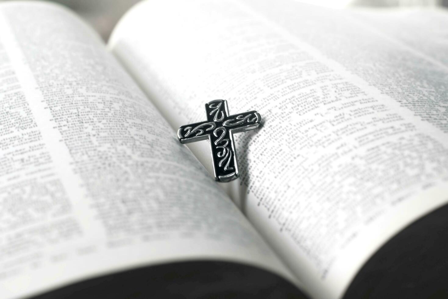 Closeup image of metal cross which places on opending bible book, soft focus, concept for religious lifestyle of christian people around the world. photo