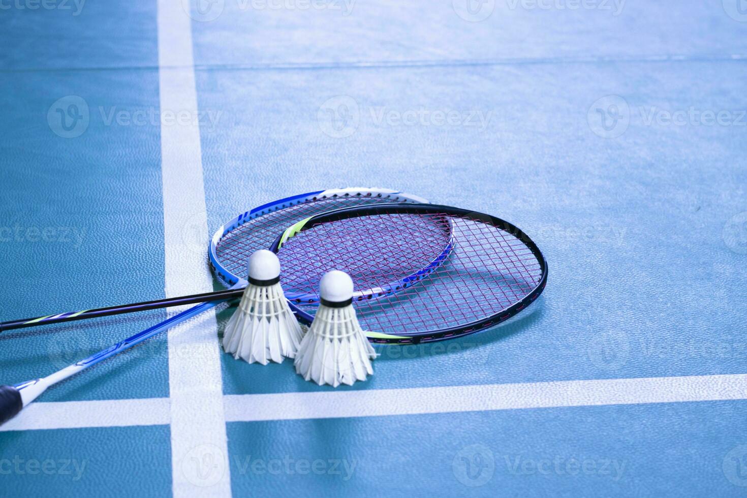 Cream white badminton shuttlecock and racket on floor in indoor badminton court, copy space, soft and selective focus on shuttlecocks. photo