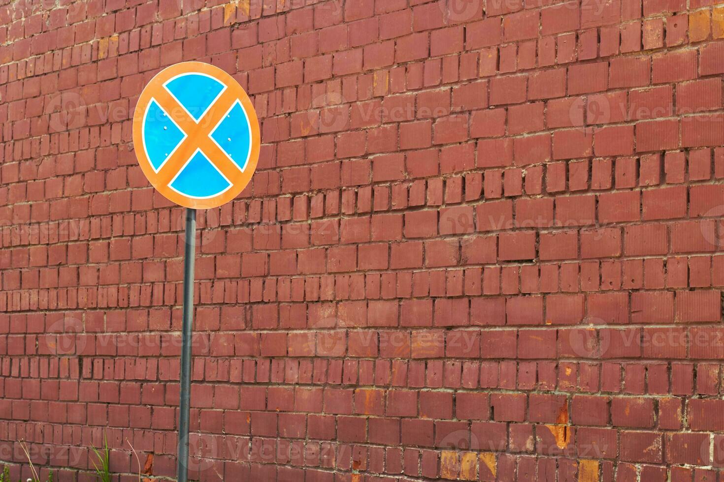 red brick wall and road round crossed out sign. photo