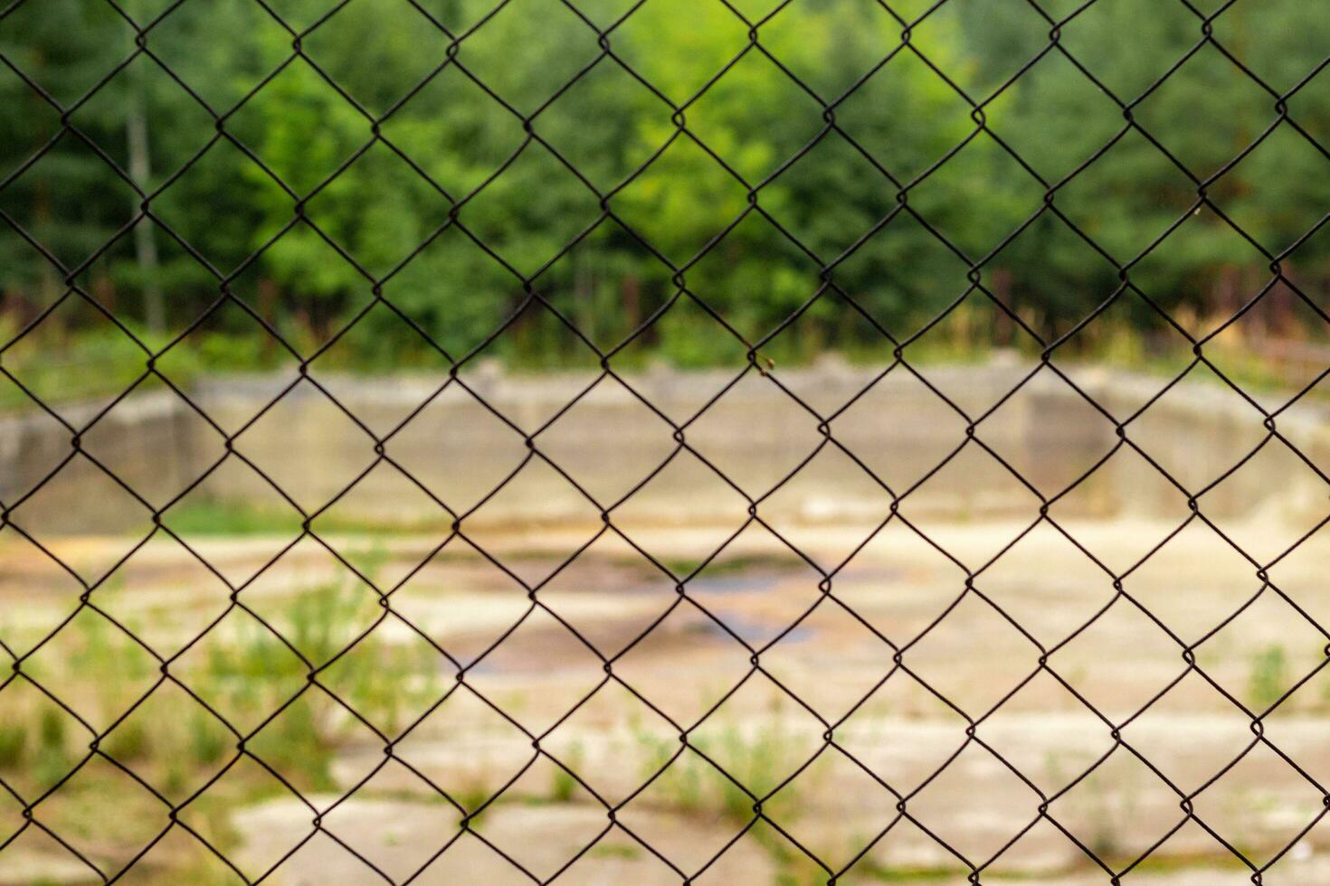 old unused swimming pool behind the netting . photo