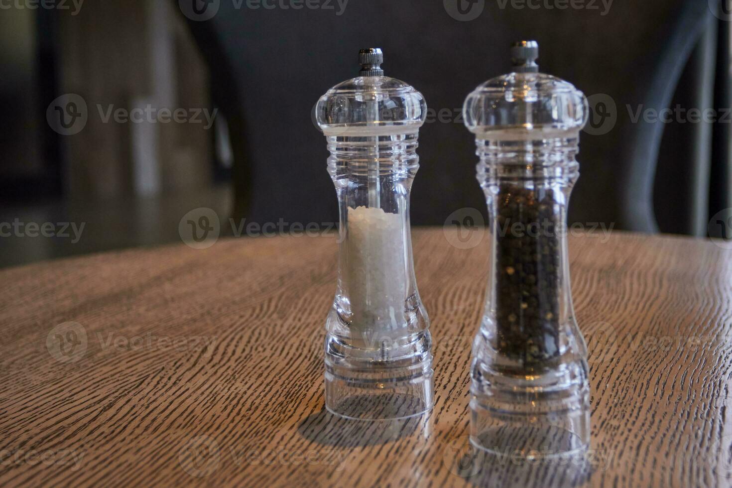 salt pepper in glass flasks on wooden table. photo