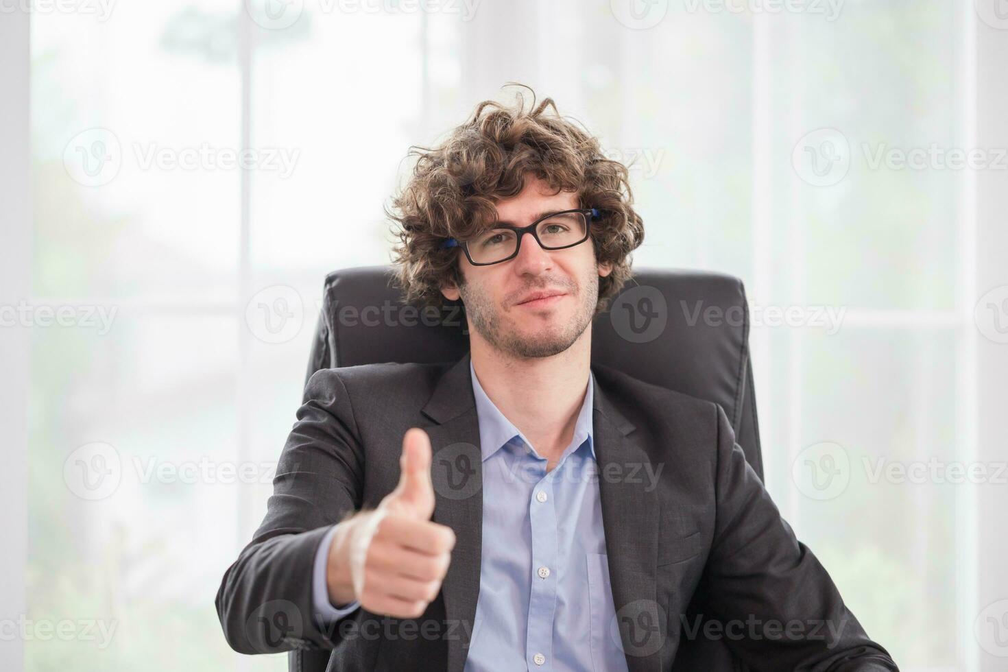 Cheerful businessman showing thumbs up in the office, Young man doing happy thumbs up photo