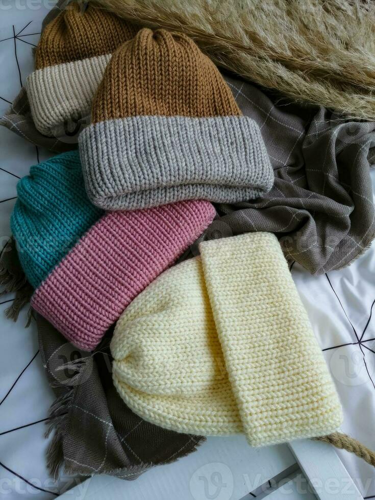 Multicolored knitted winter hats on the background of a white and gray plaid photo