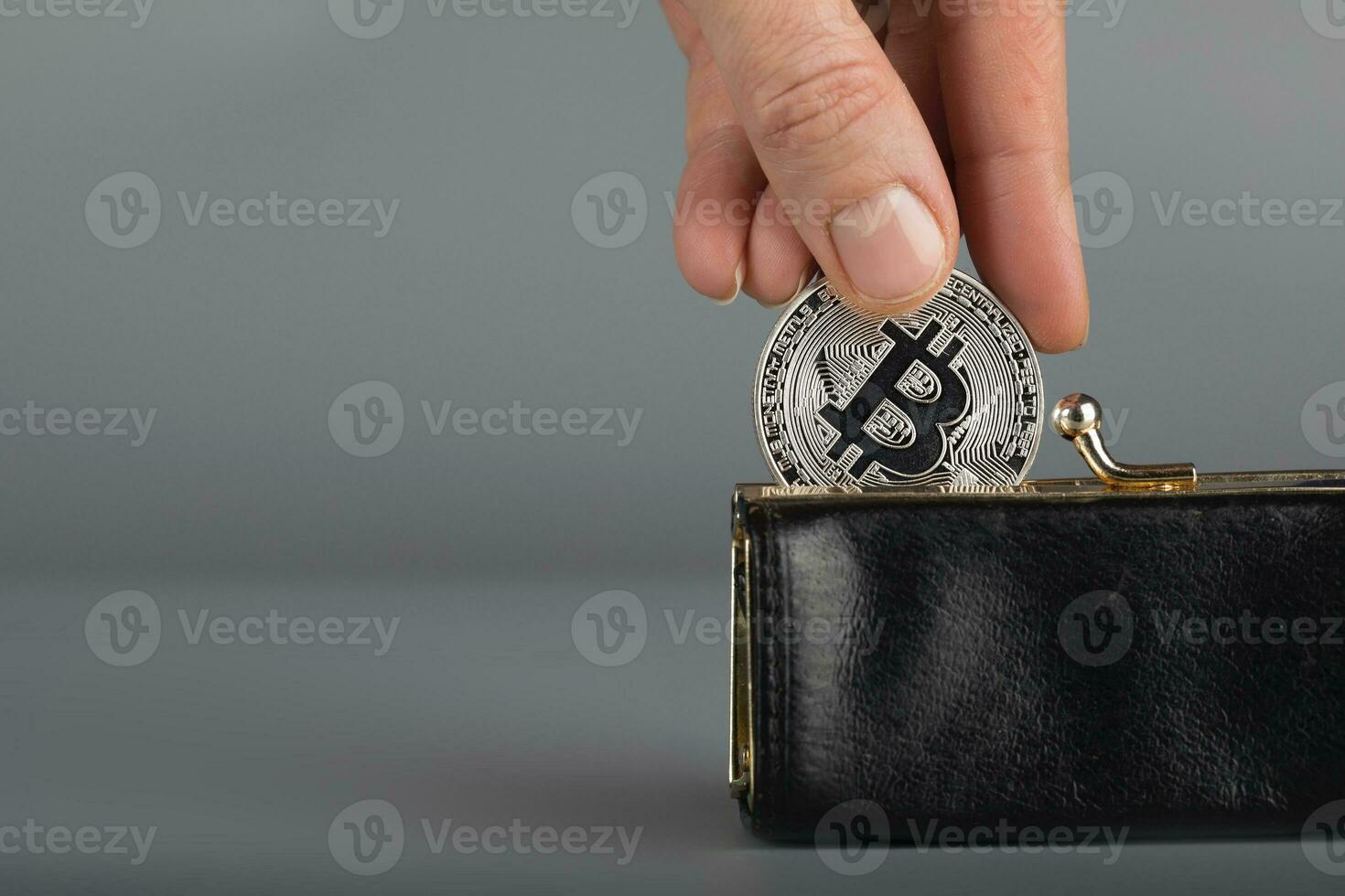 Person puts bitcoin in a black wallet. photo