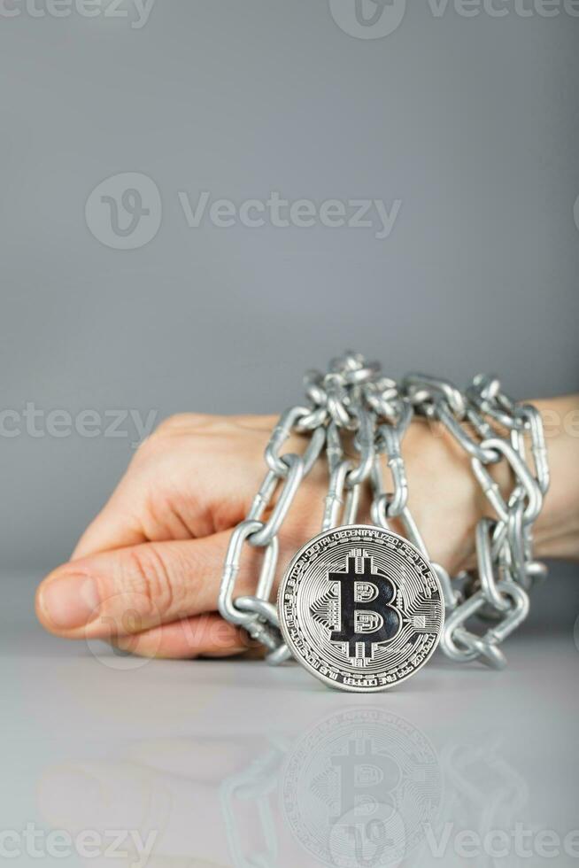 View at bitcoin. Hand bound by metallic chain in the background. photo