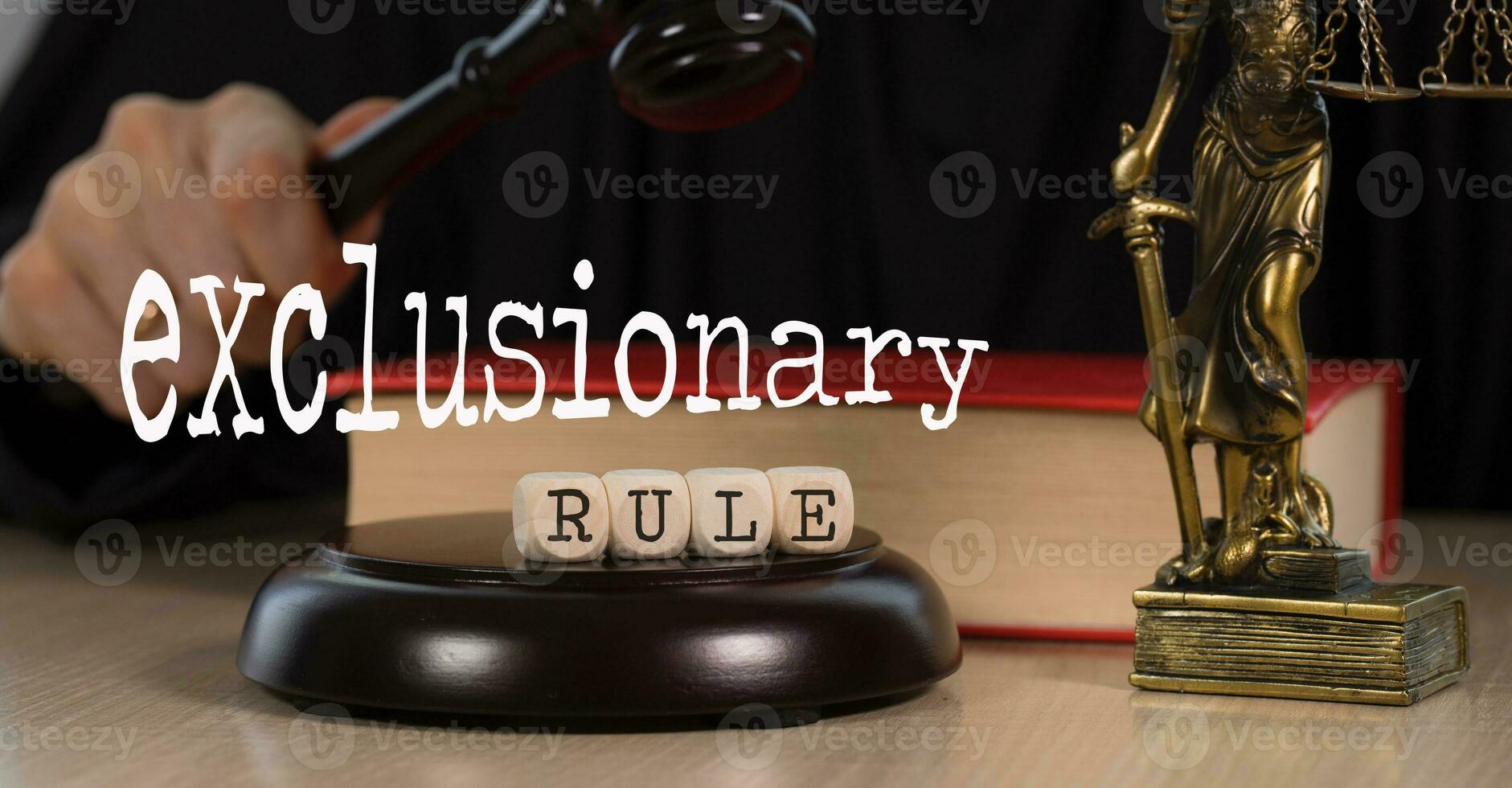 Word EXCLUSIONARY RULE composed of wooden dices. Wooden gavel and statue of Themis in the background. photo