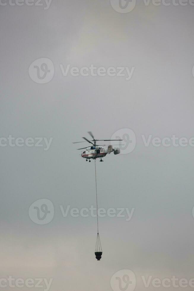 helicóptero de estado emergencia Servicio es trayendo el agua en el Cubeta foto