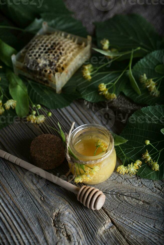 Linden blossoms honey in a glass bottle on a wooden surface. photo