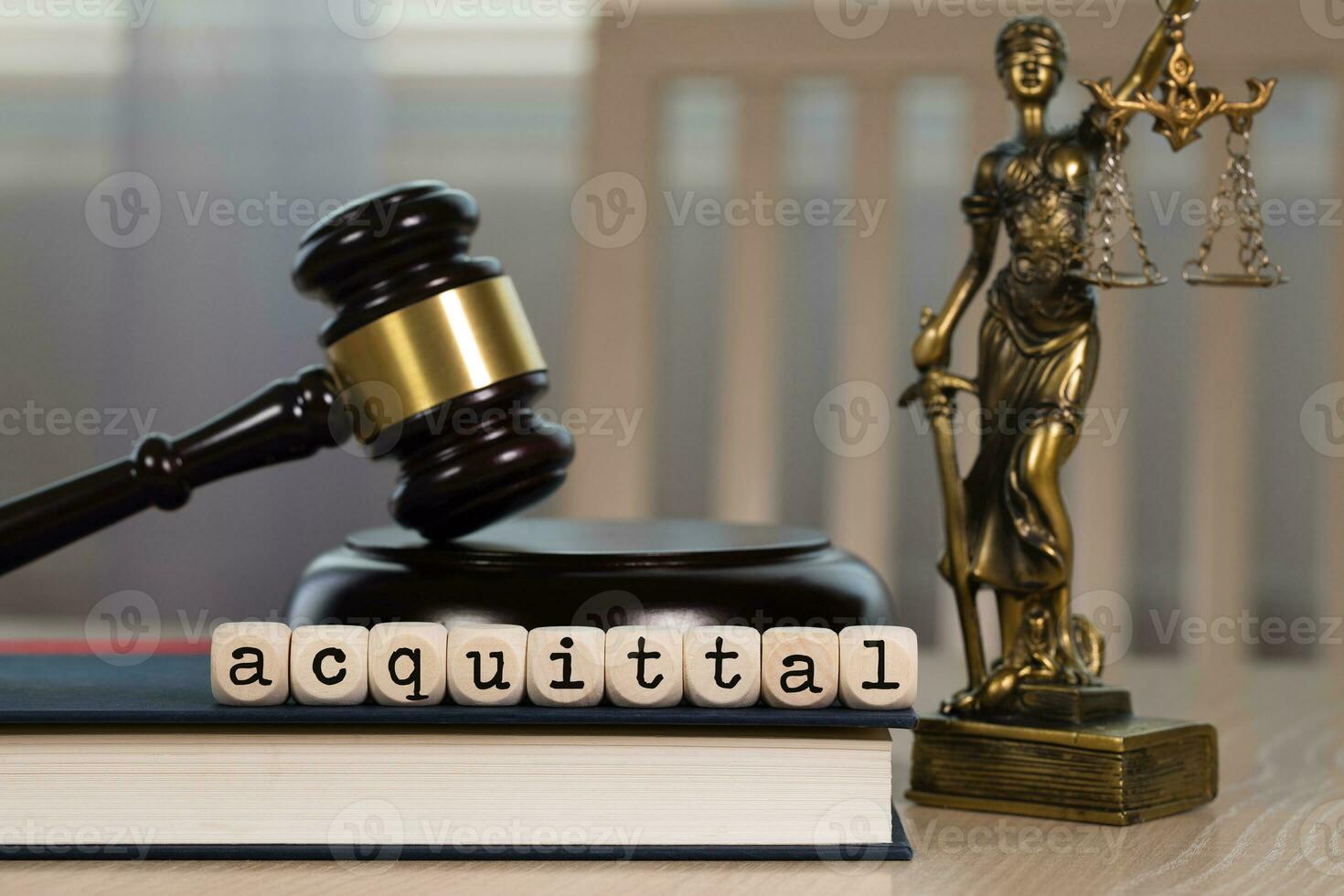 Word  ACQUITTAL composed of wooden dices. Wooden gavel and statue of Themis in the background. photo