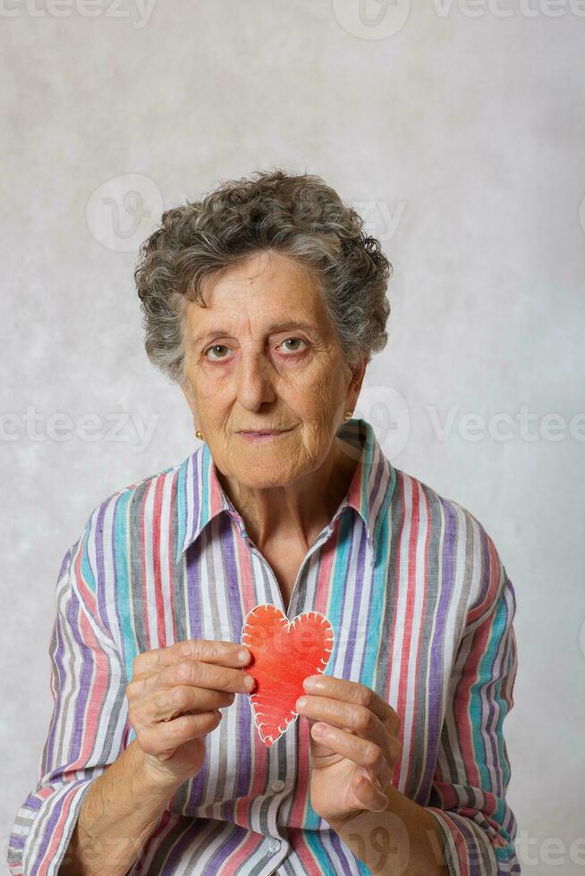 Old woman keeps a heart in her hands photo