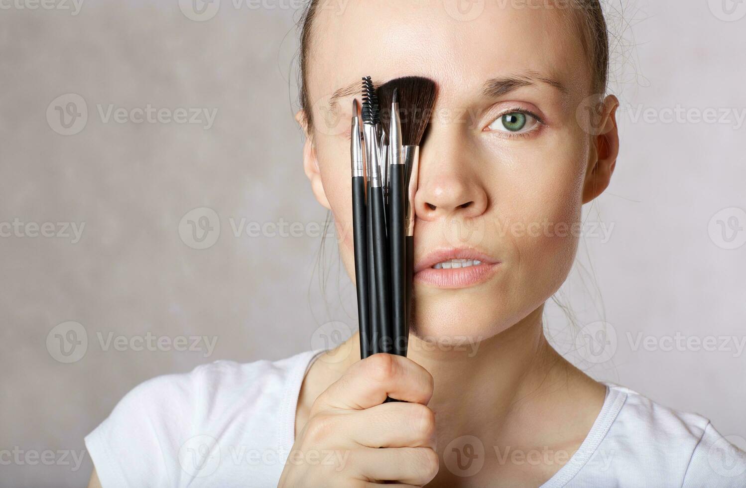 Young lady keeps make up brushes kit close to her face. Closeup photo