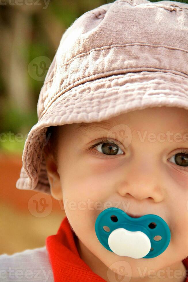 Boy of one year old in summer hat and with soother. photo