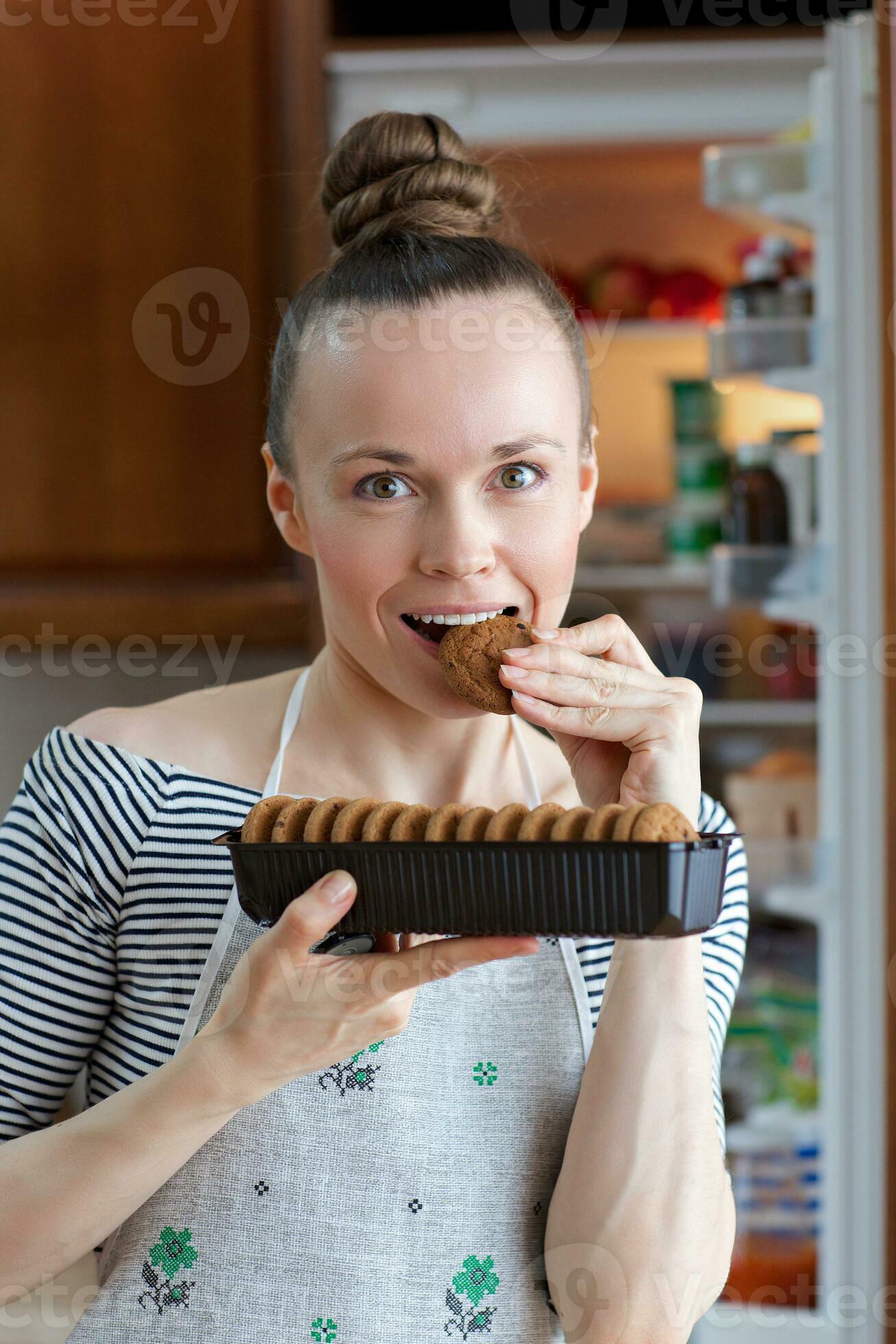 Young lady between is staying in front of the fridge. 26169096 Stock