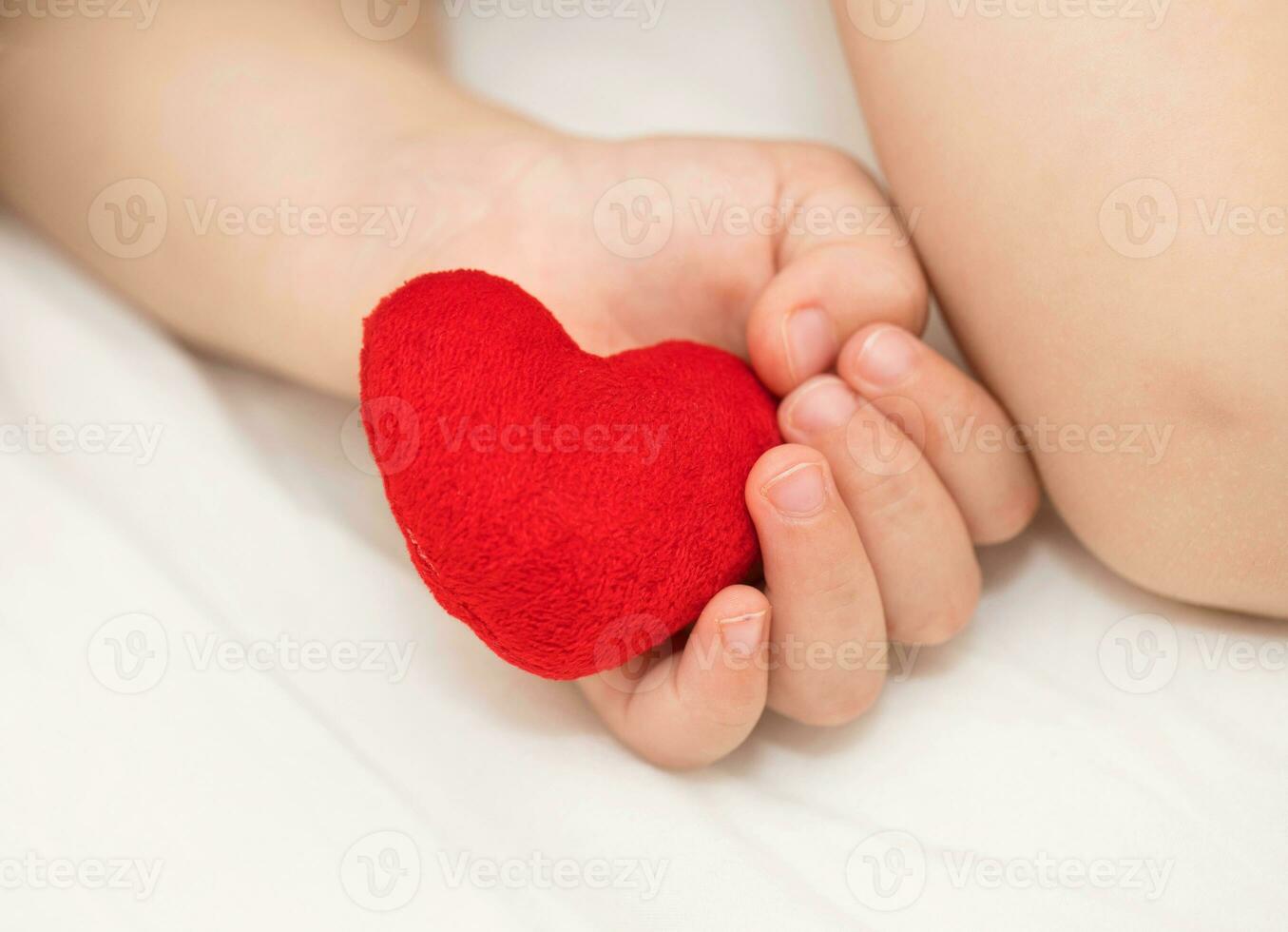 Toddler keeps red plush heart photo