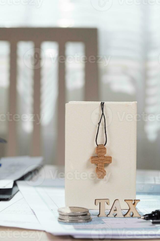 Small bible with wooden cross and word TAX in the background. photo