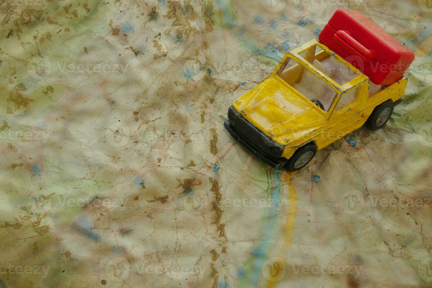 Mini car and a red plastic suitcase on a map. Closeup photo