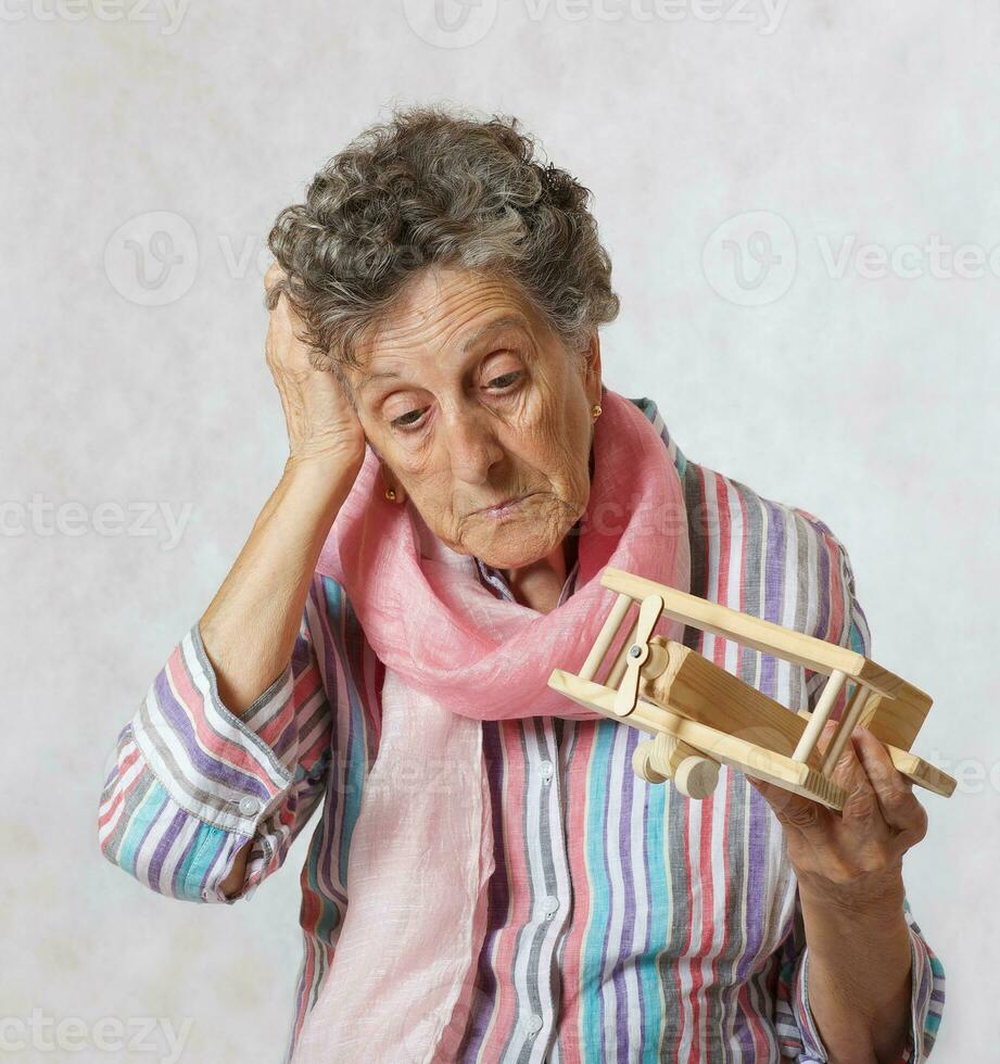 Old woman and wooden made airplane. photo