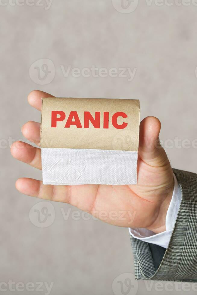 Word PANIC. Man keeps finished toilet paper roll photo