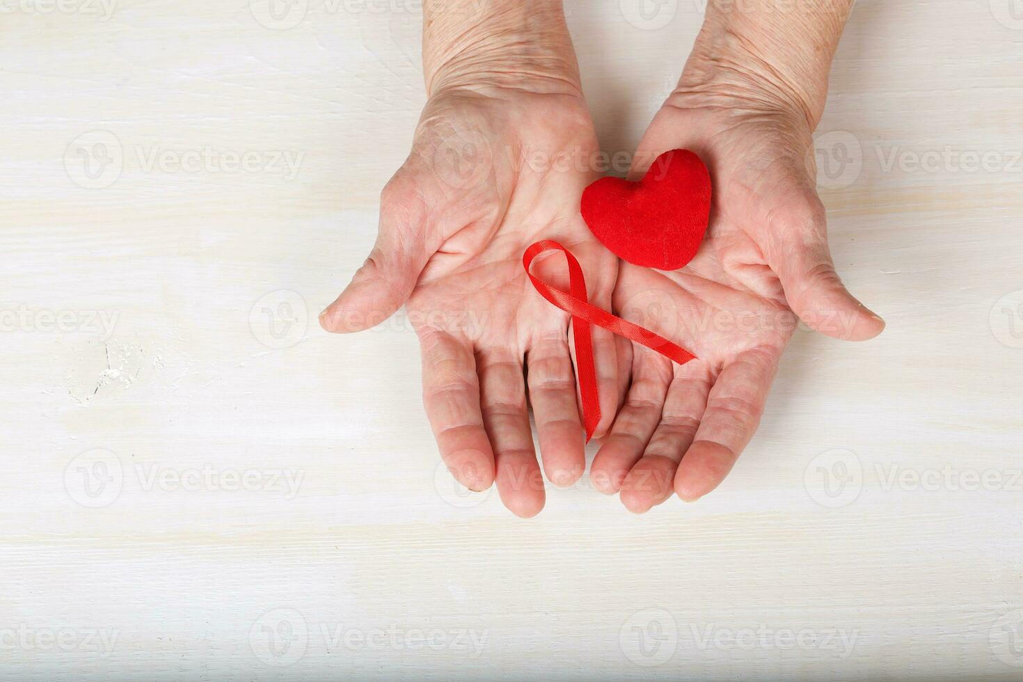 Old woman and a plush red heart. Closeup photo