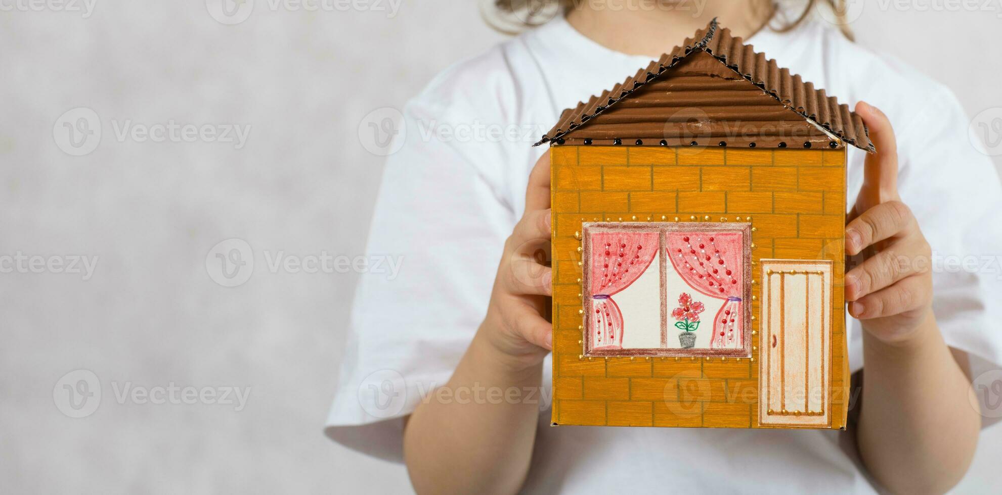 Boy of five years is keeping handmade carton paper house. photo