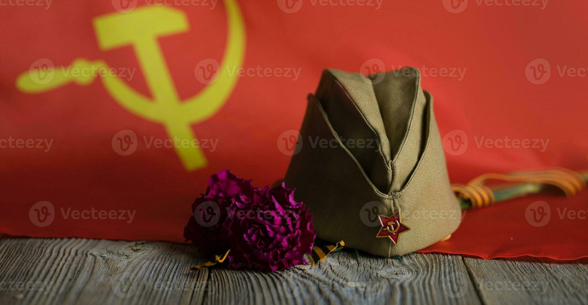 Military cap, carnations, Saint George ribbon on a wooden surface. photo