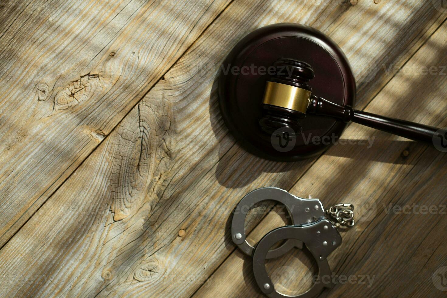 Wooden gavel and handcuff on a wooden surface. photo