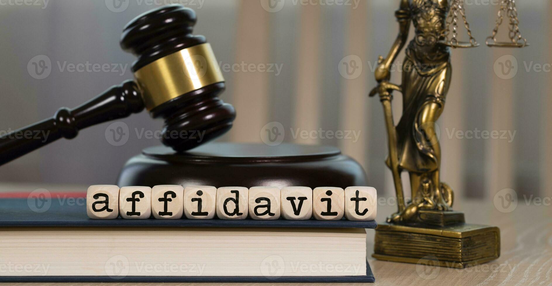 Word AFFIDAVIT composed of wooden dices. Wooden gavel and statue of Themis in the background. photo