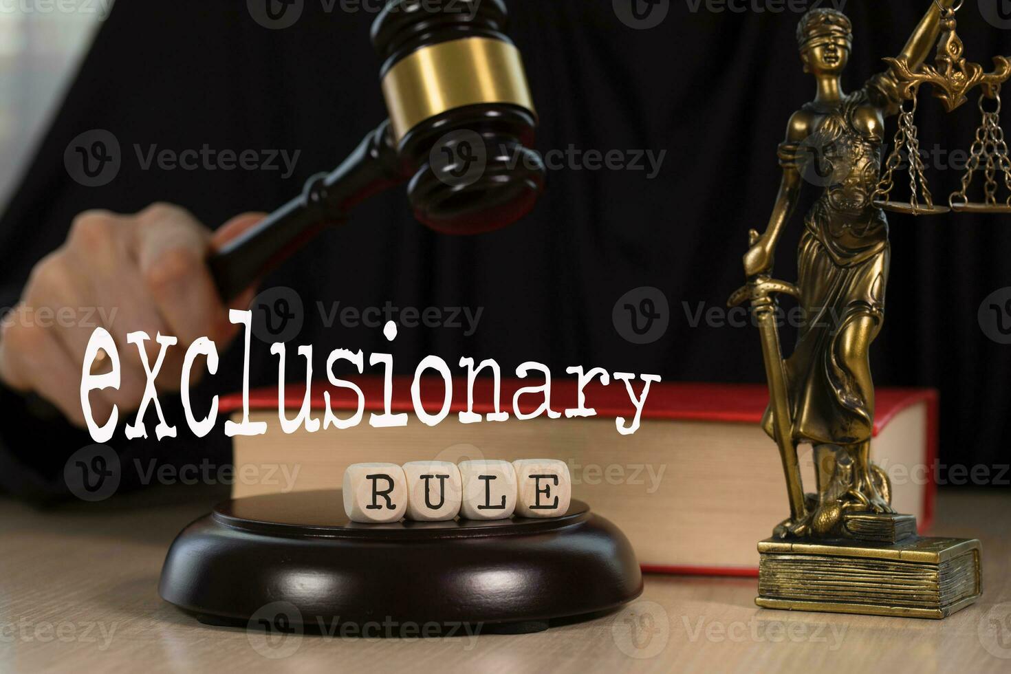 Word EXCLUSIONARY RULE composed of wooden dices. Wooden gavel and statue of Themis in the background. photo