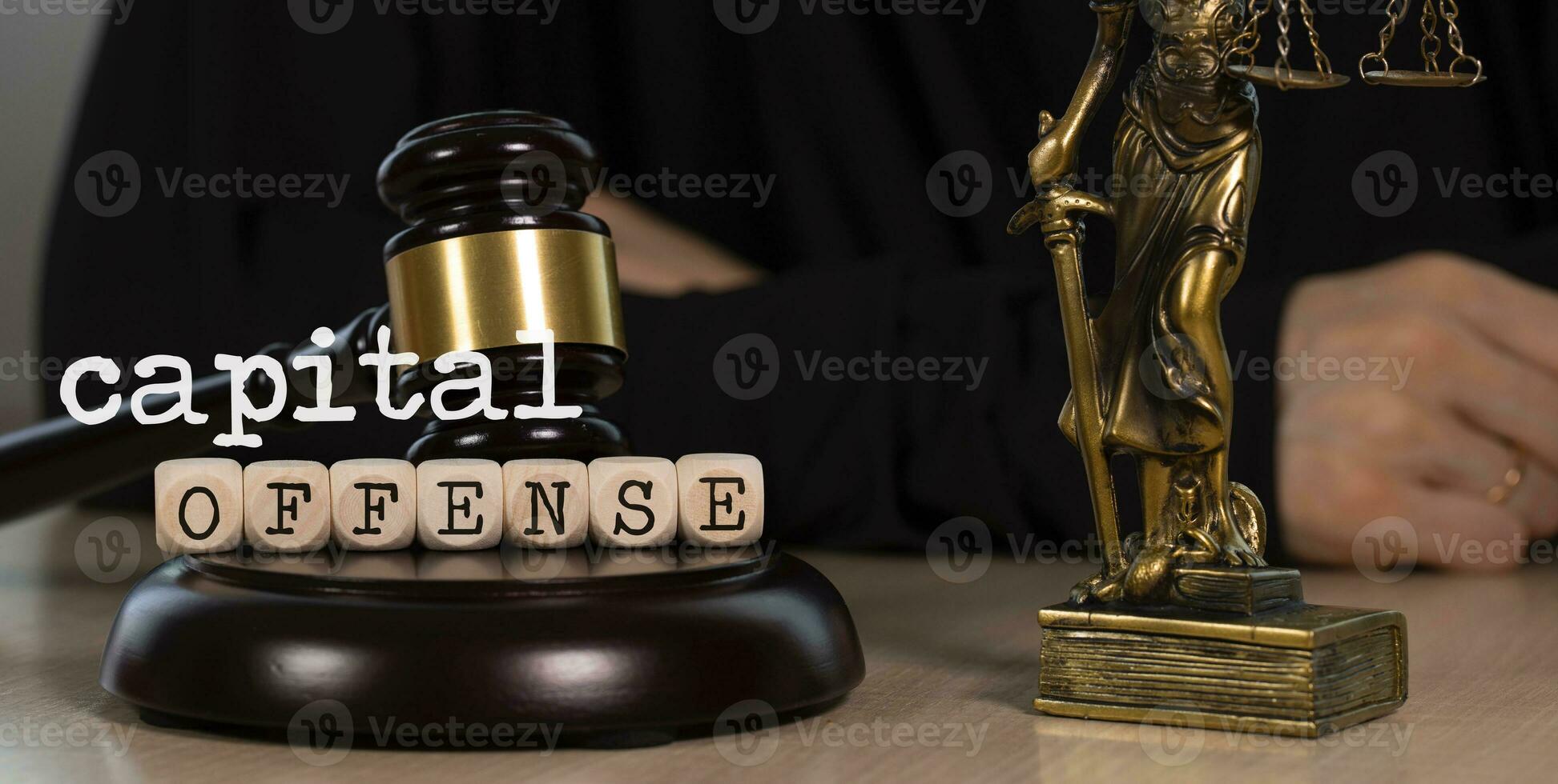 Words CAPITAL OFFENSE composed of wooden dices. Wooden gavel and statue of Themis in the background. photo