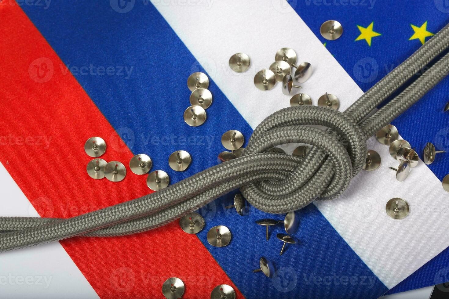 Two flags of EU and Russia,rope with a knot and pins. Background photo