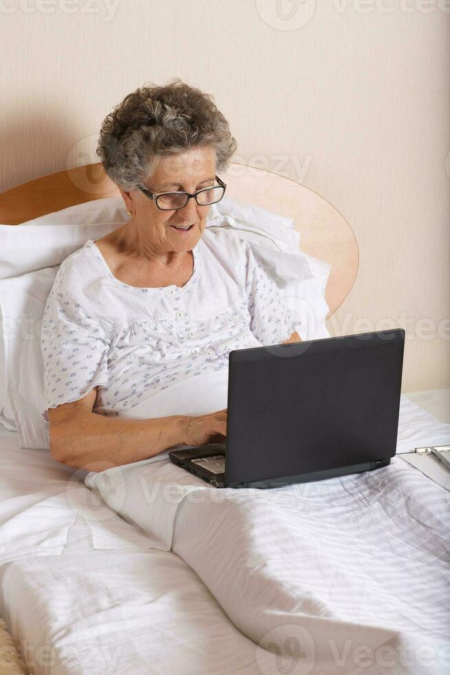Old woman is communicating through her computer wit hrelatives photo