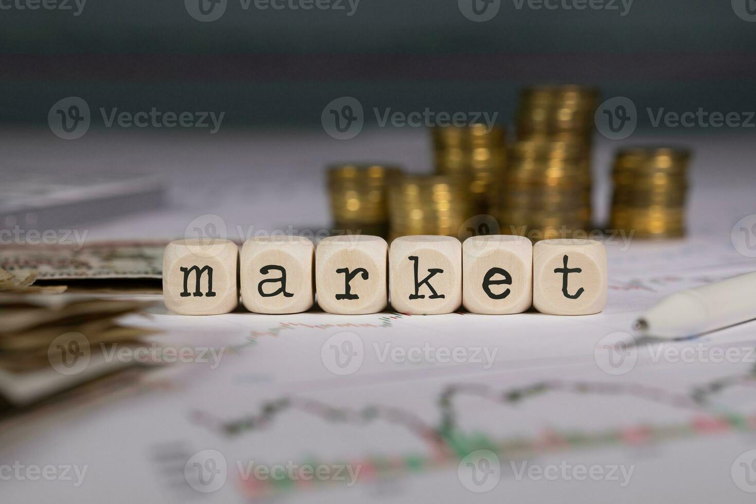 Word MARKET composed of wooden letter. Stacks of coins in the background. photo