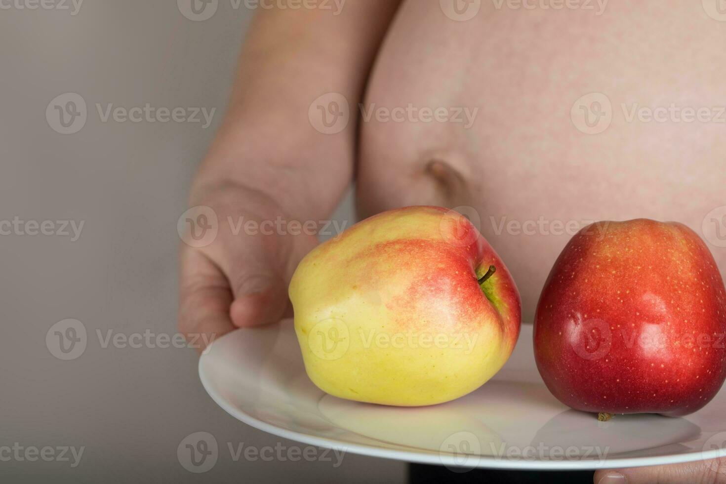 Young pregnant woman keeps a white plate with red apples on it. photo