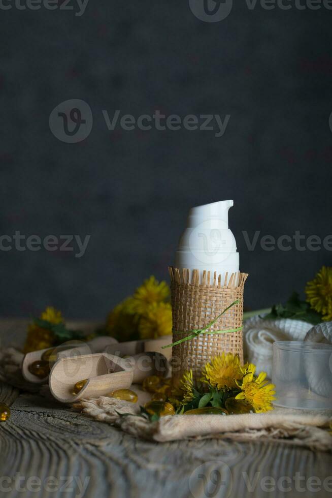 Cream with dandelion extract in a white plastic bottle on a wooden surface. photo