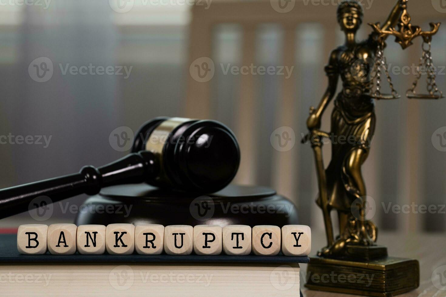 Word BANKRUPTCY composed of wooden dices. Wooden gavel and statue of Themis in the background. photo