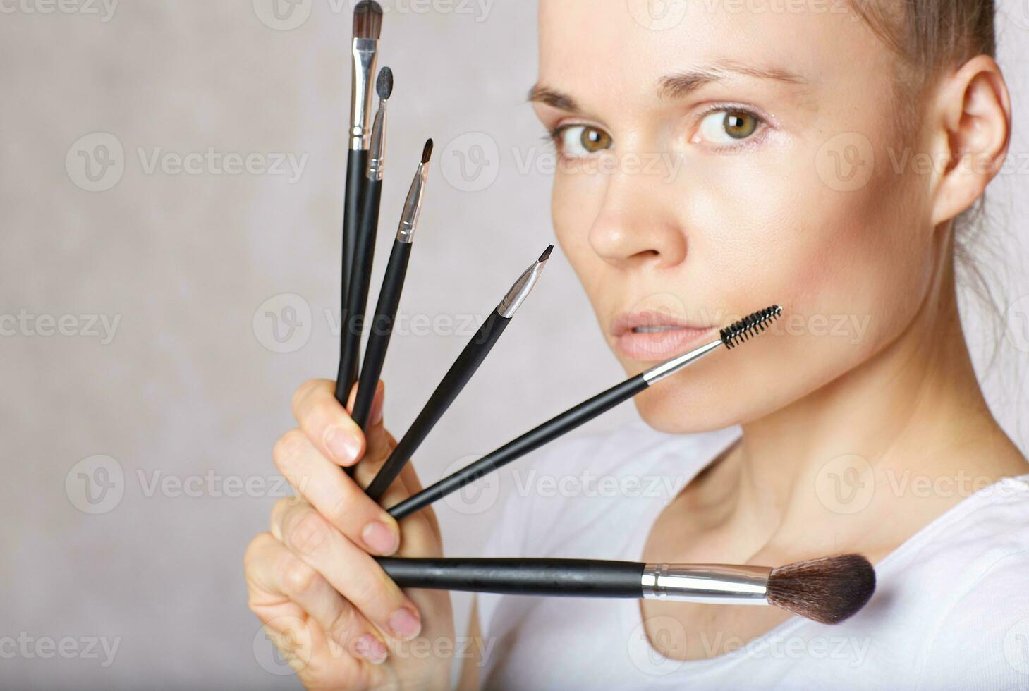 Make up brushes kit close to her face of a young lady. Closeup photo