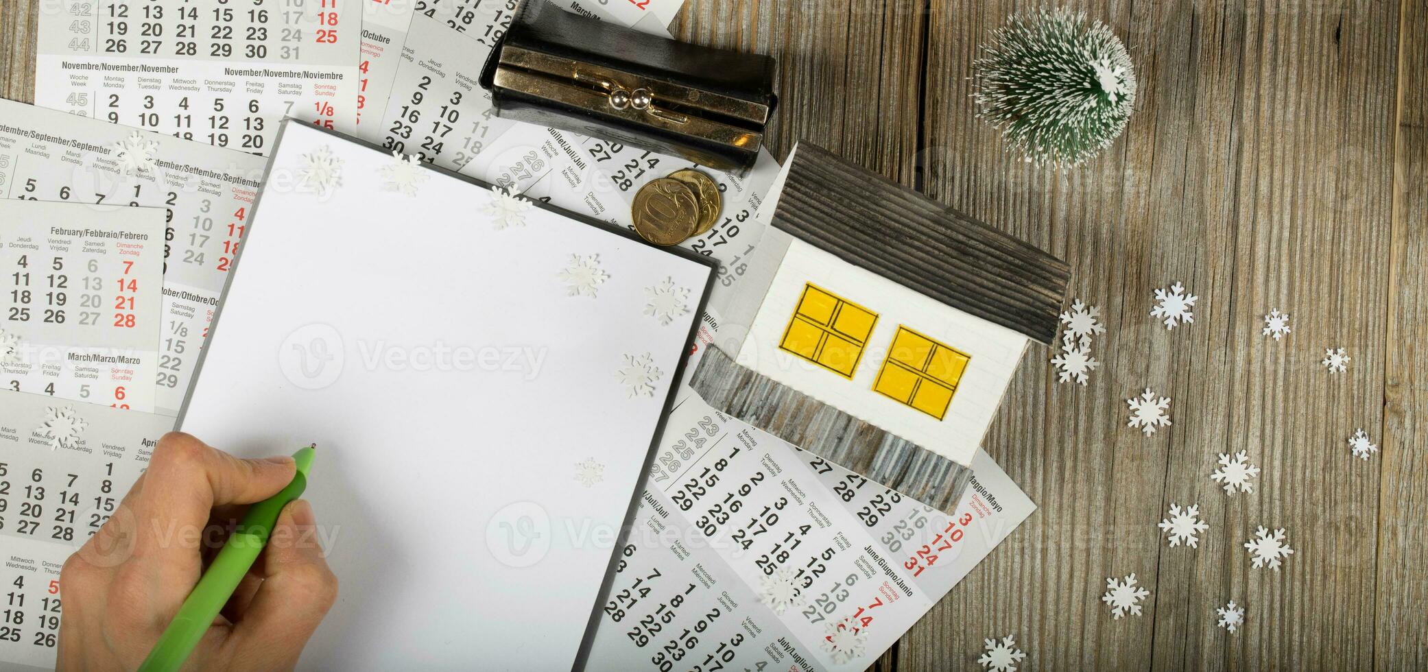 Blank sheet of paper and small paper house with coins on winter background. photo