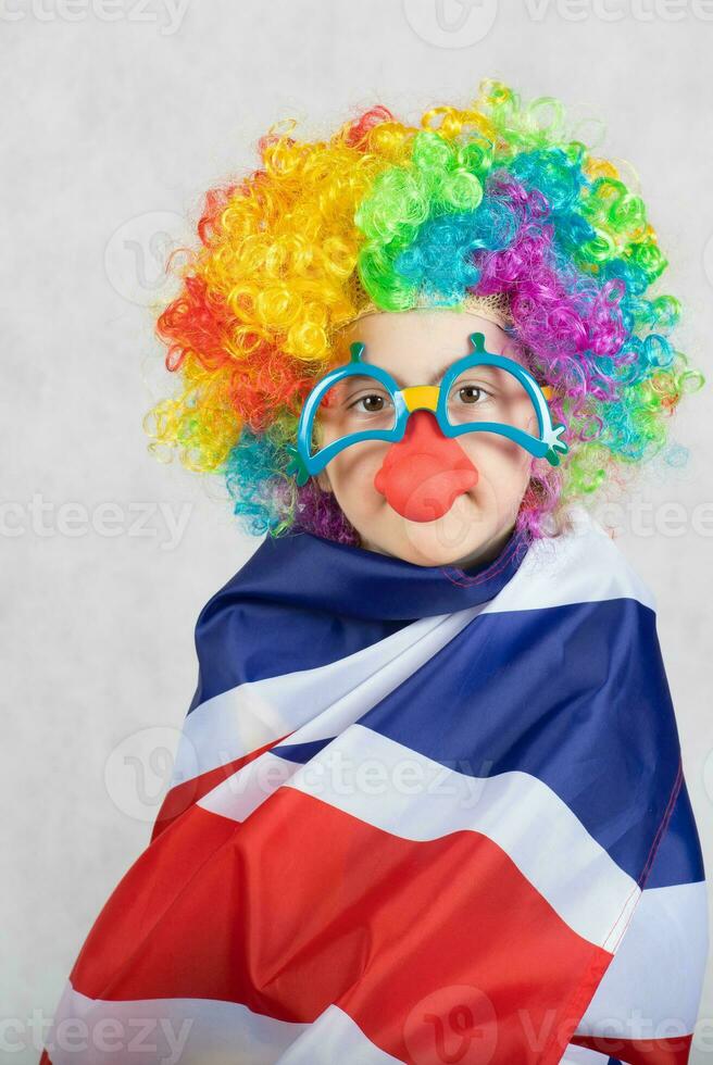 Boy dressed in the costume of a clown covered himself with British flag. photo