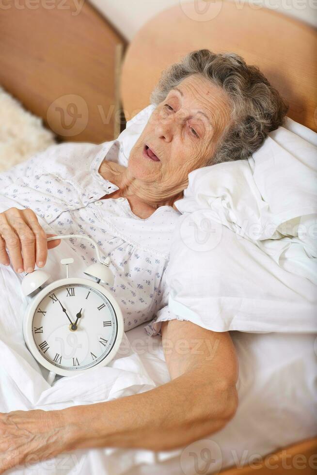 Old woman with vintage alarm clock photo