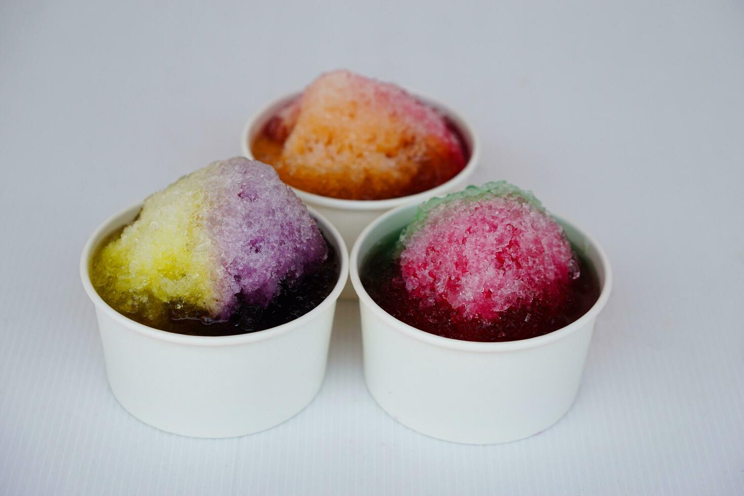 Shaved ice smoothie dessert. Concept, Thai traditional local dessert for hot weather in summer. Crunch ice flakes , topping with colorful fruit flavor syrup and condensed milk. Sweet condiments. photo