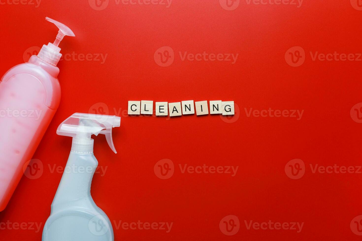 Flat lay cleaning products and sponges on a red background. Word cleaning from letters. Cleaning Spray Mockup photo