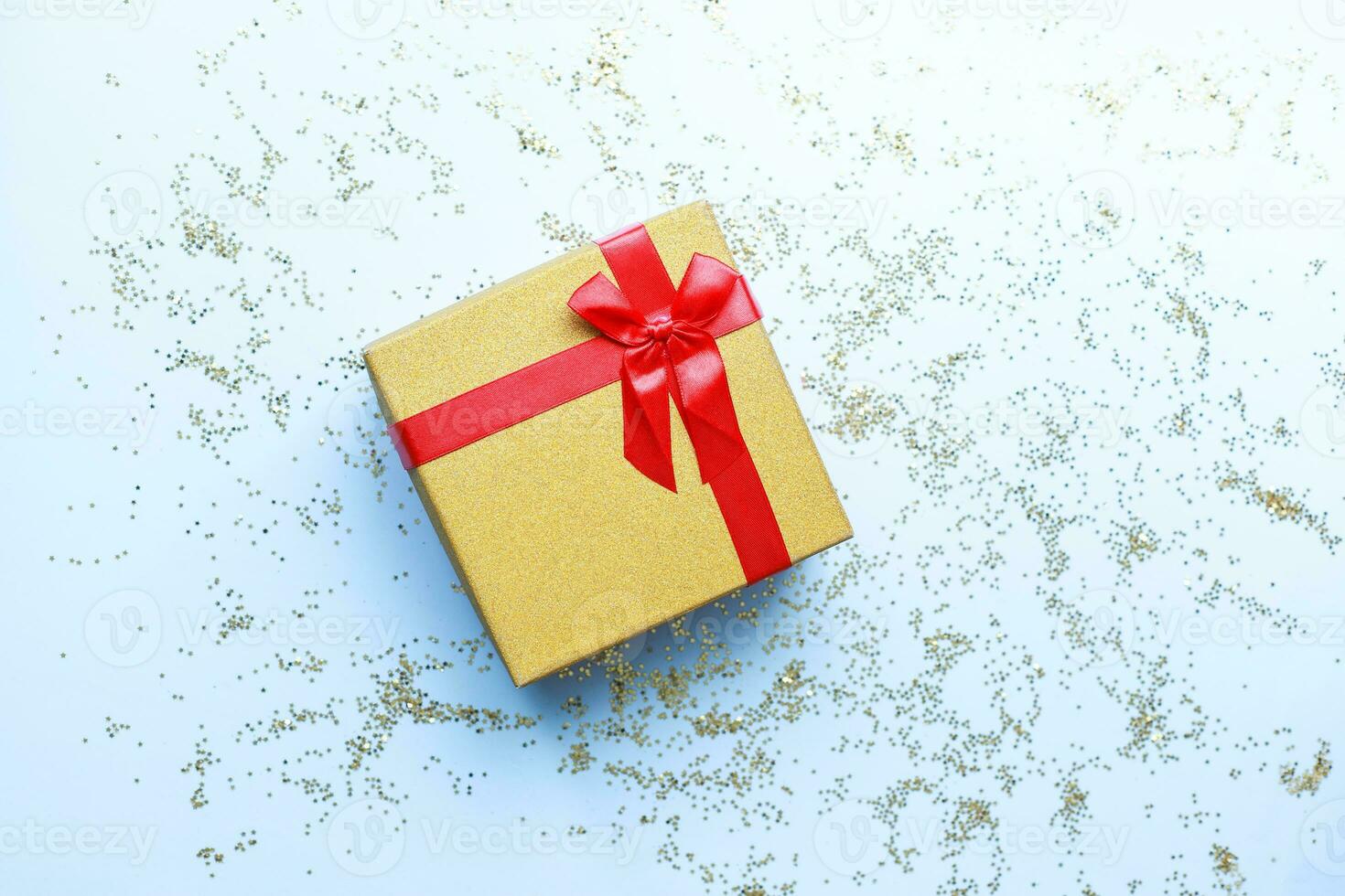 Flat lay gift on blue background. Box with red bow and glitter. photo
