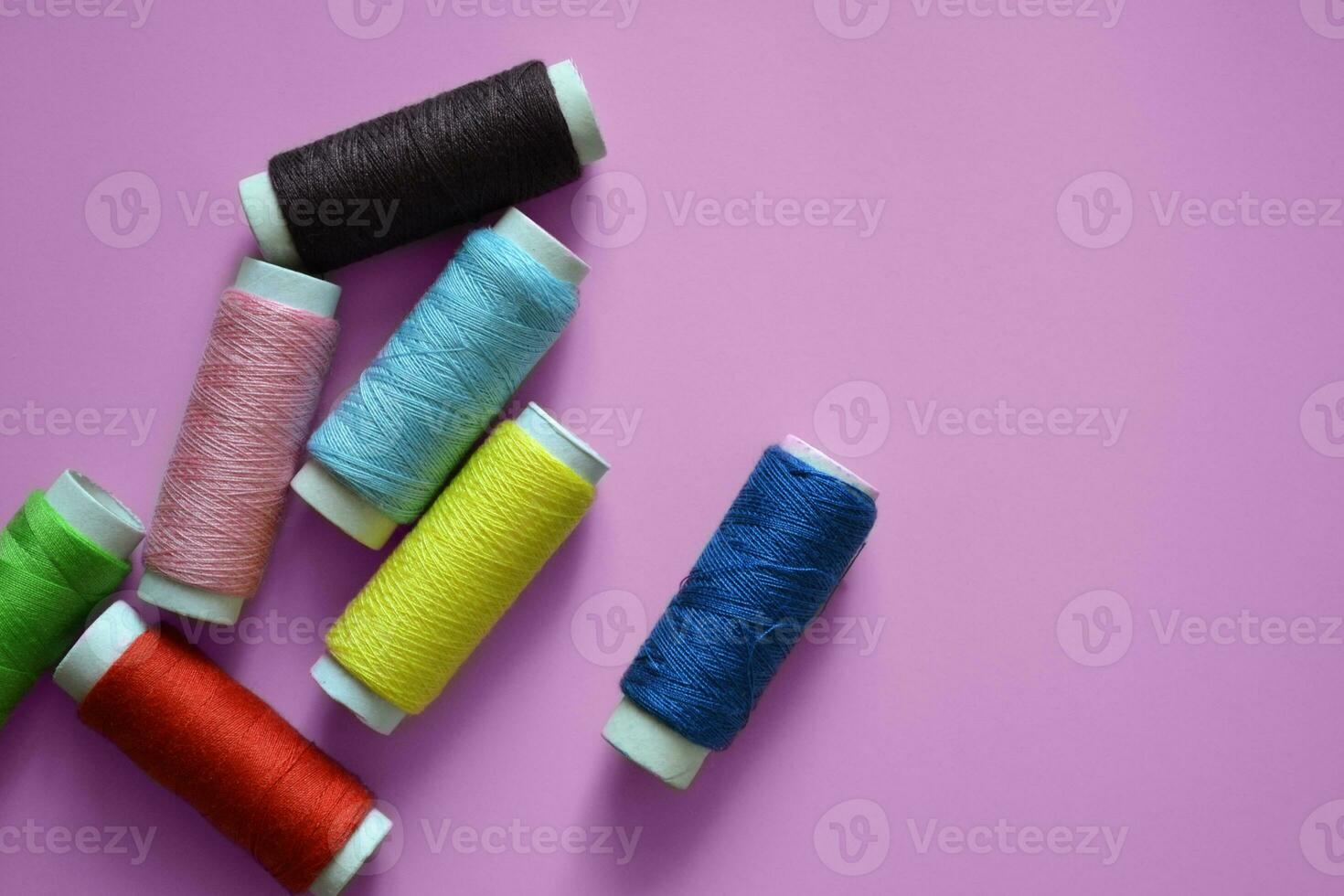 spools of thread on a pink background, a banner for an atelier, tailoring, sewing threads, photos for a textile factory