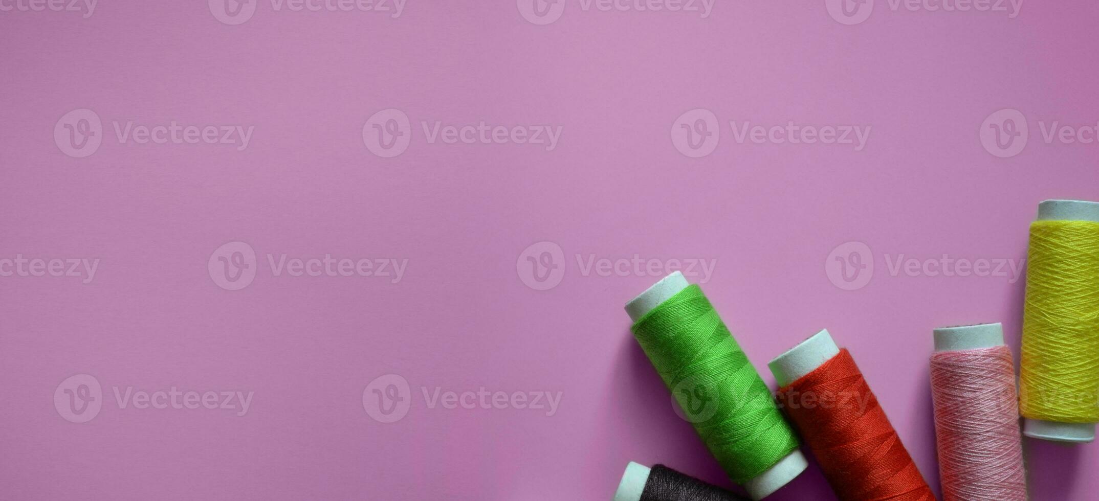 spools of thread on a pink background, a banner for an atelier, tailoring, a photo for a sewing workshop, sewing threads, a place for text