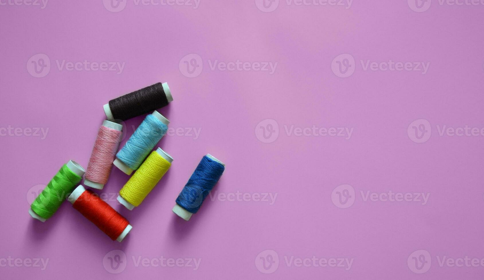 spools of thread on a pink background, a banner for an atelier, tailoring, sewing threads, photos for a textile factory, a place for text