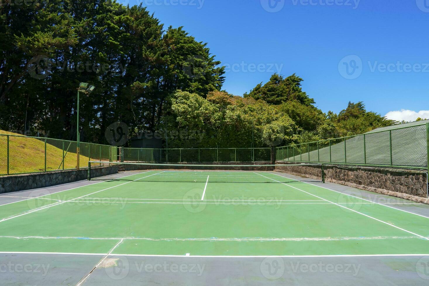 Empty outdoor tennis court with marking lines and net fence photo