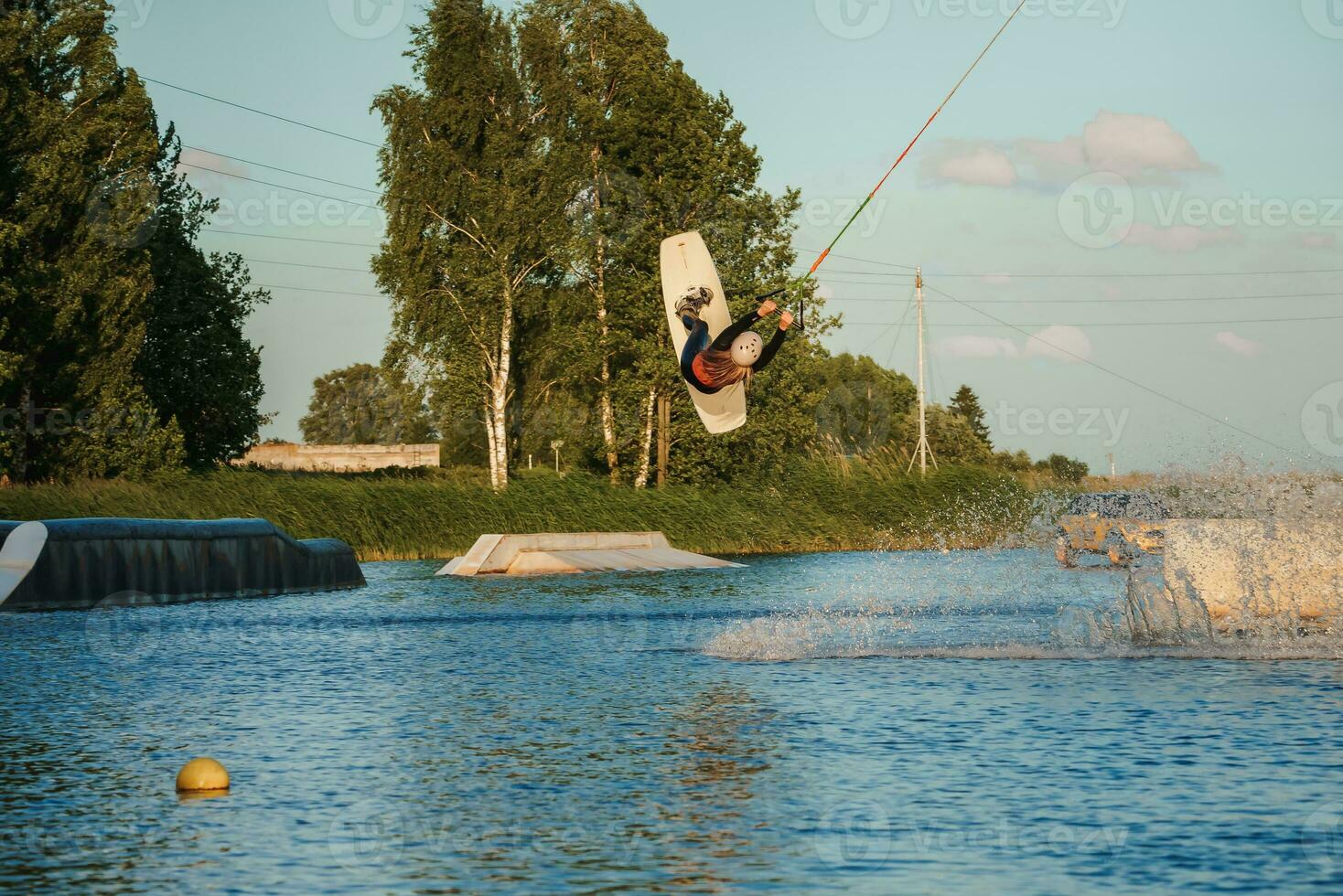 Wake boarding female sportsman girl jumping high wake boarding raley trick with huge water splash in the cable park photo