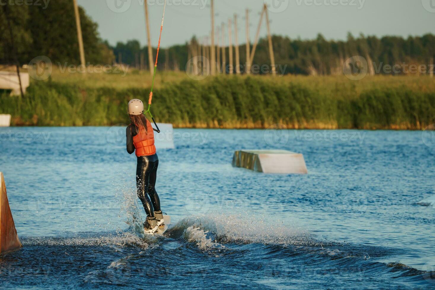Wake boarding female sportsman girl jumping high wake boarding raley trick with huge water splash in the cable park photo
